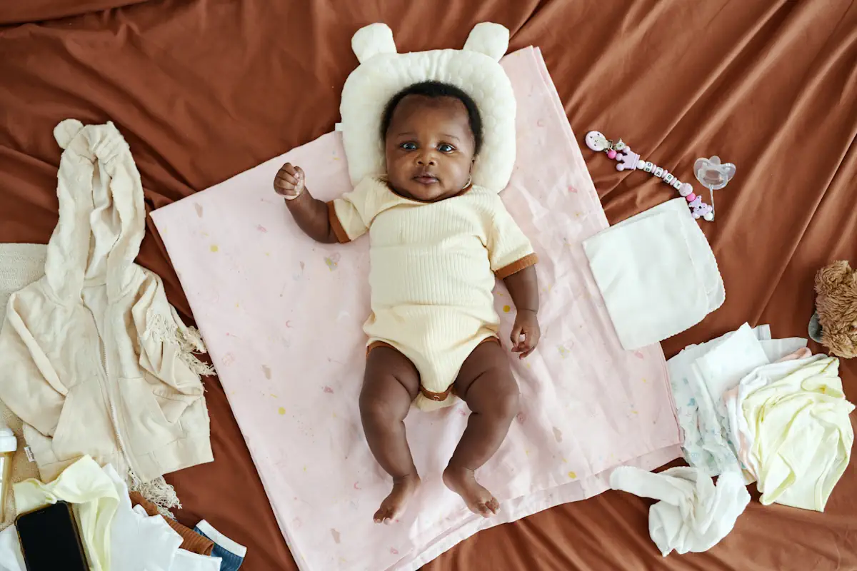 Un bébé allongé sur le dos sur une couverture avec quelques accessoires pour bébé à côté
